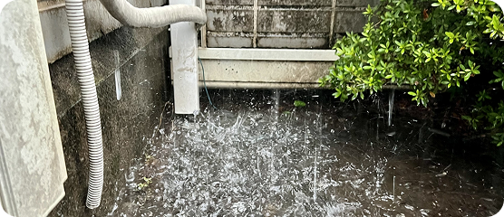 豪雨によって建物の基礎周辺に水たまりができ、雨水がはね上がっている様子