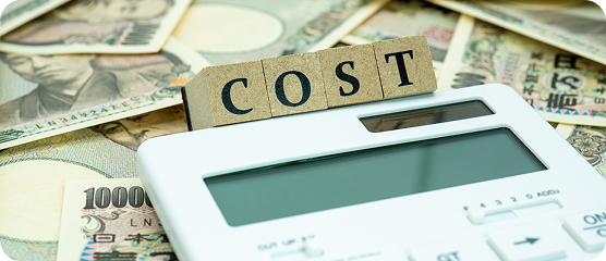 「COST」の文字と電卓、そして日本円紙幣が並べられたコストに関するイメージ