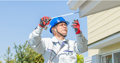 作業員がメジャーで住宅の軒先部分を計測している様子