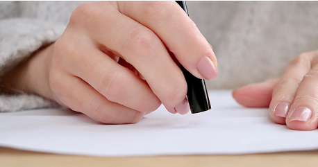 書類に署名をする人物の手元のアップ