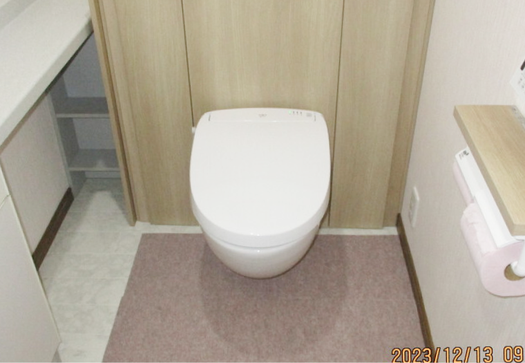 ベージュの壁と白い便器が設置された清潔感のあるトイレ空間