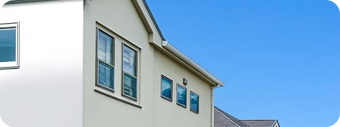 青空を背景にした白い外壁の戸建住宅の一部外観