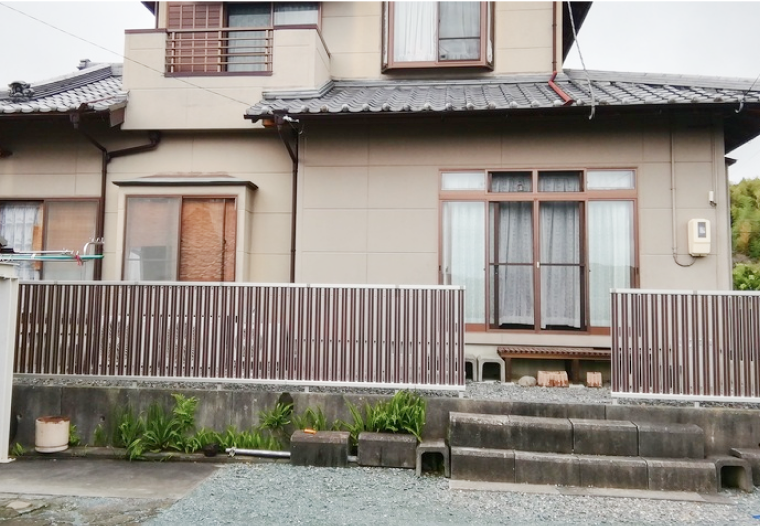 和風住宅の外観と植え込み、手前にフェンスが並ぶ様子